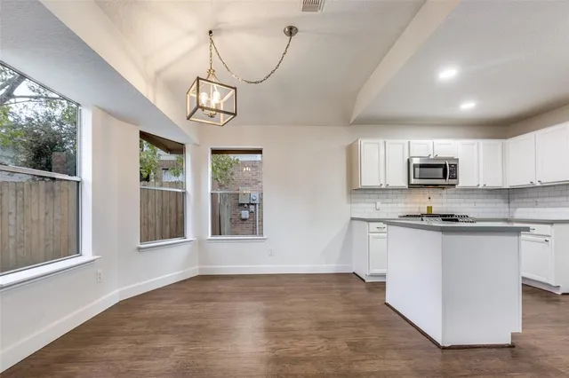 a view of a kitchen with stainless steel appliances granite countertop a stove a sink dishwasher a microwave oven with cabinets and wooden floor