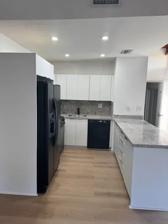 a large kitchen with stainless steel appliances kitchen island granite countertop a refrigerator and a stove top oven