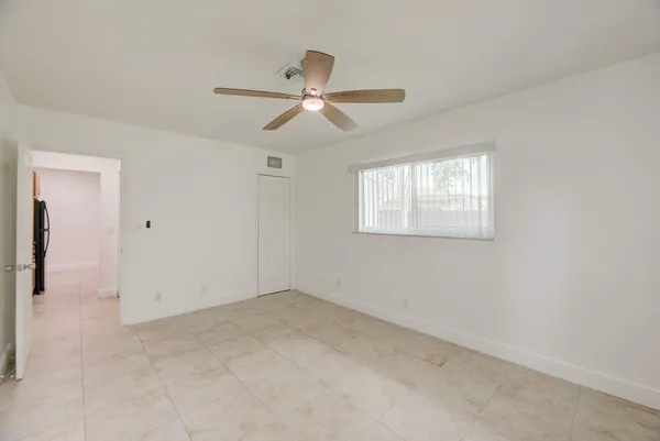 an empty room with windows and fan