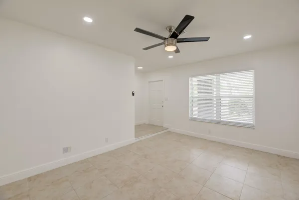 an empty room with a window and a fan