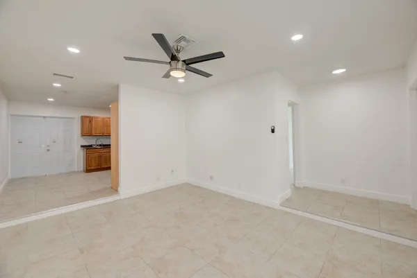 an empty room with a ceiling fan and windows