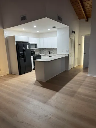 a large white kitchen with kitchen island a sink a stove a refrigerator and a sink