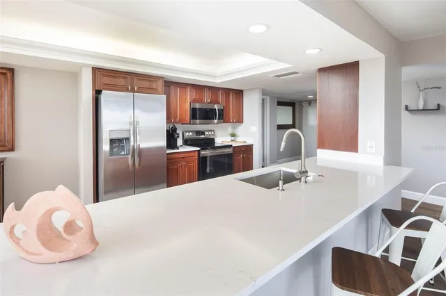 a kitchen with stainless steel appliances kitchen island granite countertop a sink refrigerator and cabinets