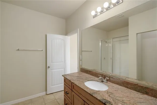 a bathroom with a granite countertop sink a mirror and a shower
