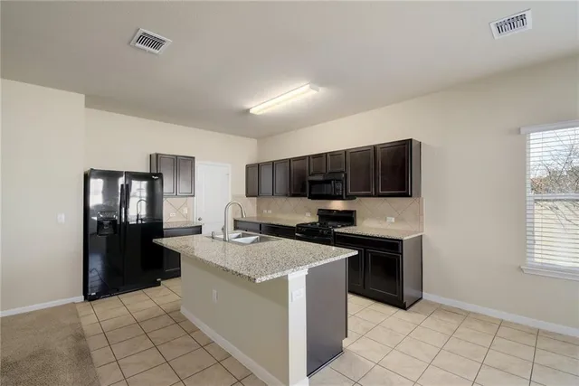 a kitchen with kitchen island stainless steel appliances a stove refrigerator sink and cabinets