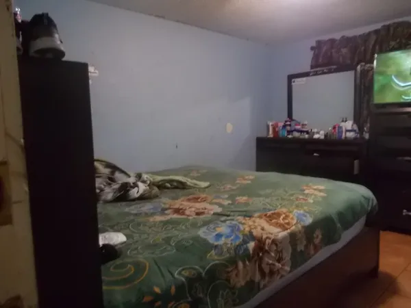 a bedroom with a bed and a flat tv screen on dresser