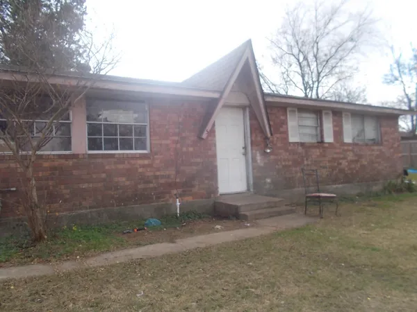 a view of a brick house with a yard and large tree