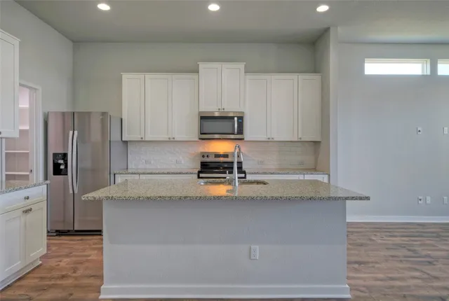 a kitchen with stainless steel appliances granite countertop a refrigerator and a stove