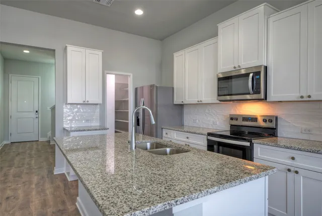 a kitchen with stainless steel appliances granite countertop a sink stove and microwave