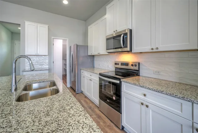 a kitchen with stainless steel appliances granite countertop a sink stove and refrigerator