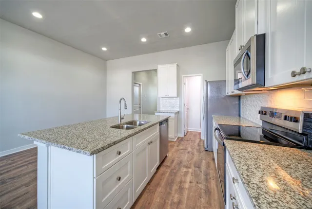 a kitchen with stainless steel appliances granite countertop a sink and a refrigerator