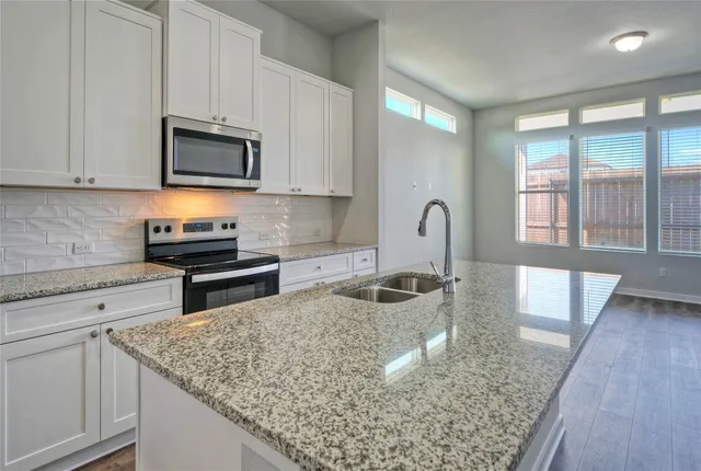 a kitchen with stainless steel appliances granite countertop a sink a stove and a wooden cabinets
