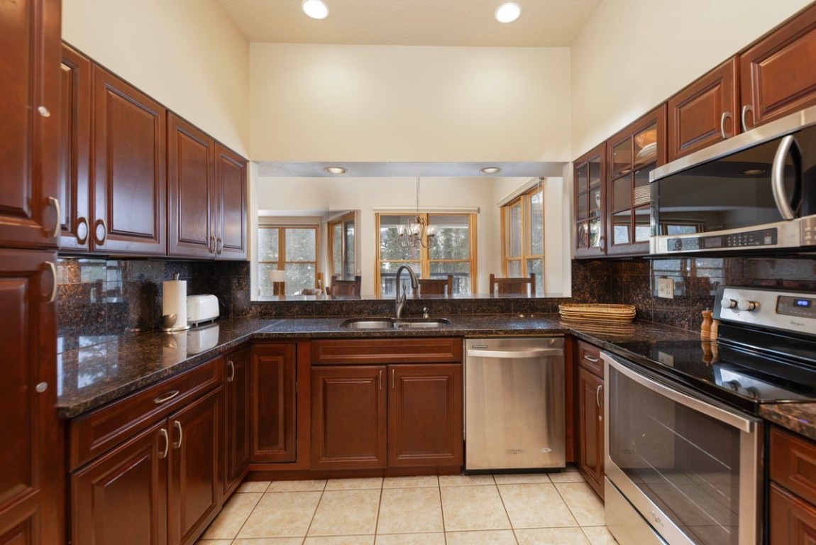 240 Tennis Club Road, Unit 1664 Keystone, CO 80435 - Photo 8 of 26 Kitchen featuring sink, appliances with stainless steel finishes, light tile patterned flooring, decorative backsplash, and dark stone counters