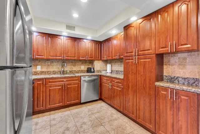 a kitchen with stainless steel appliances granite countertop wooden cabinets a sink and a refrigerator