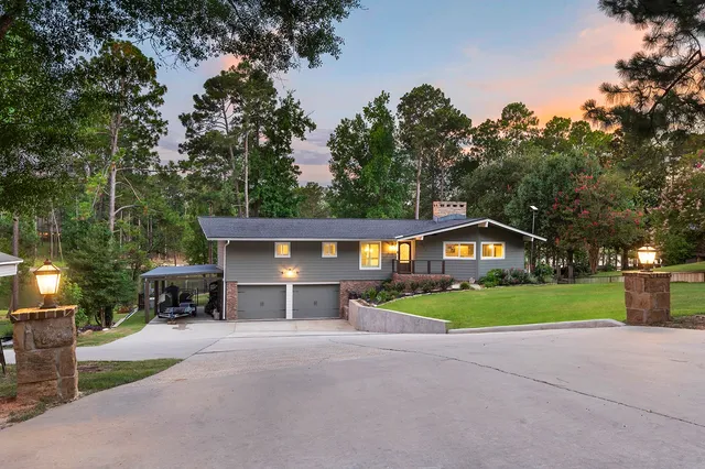 a view of a house with a yard and large trees