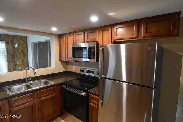 a kitchen with stainless steel appliances granite countertop a refrigerator and a sink