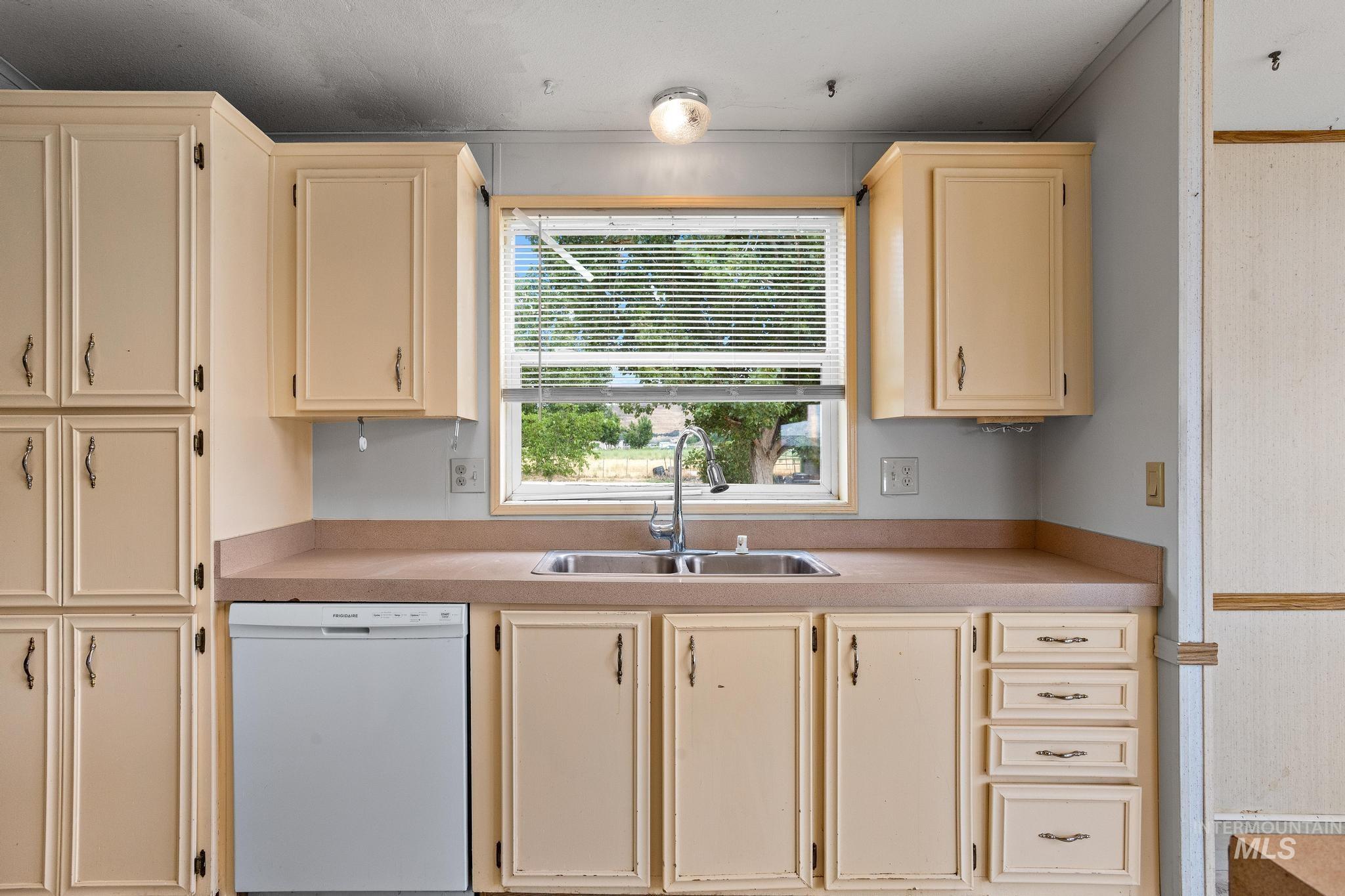 3680 South Mill Road Emmett, ID 83617 - Photo 16 of 38 Kitchen workstation featuring a dual basin sink, light-toned cabinetry, an integrated dishwasher, and a window with horizontal blinds