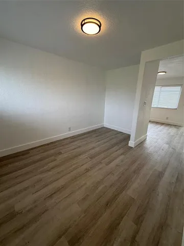 an empty room with wooden floor and window