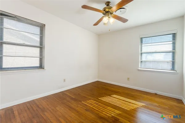 a view of a room with wooden floor and a ceiling fan