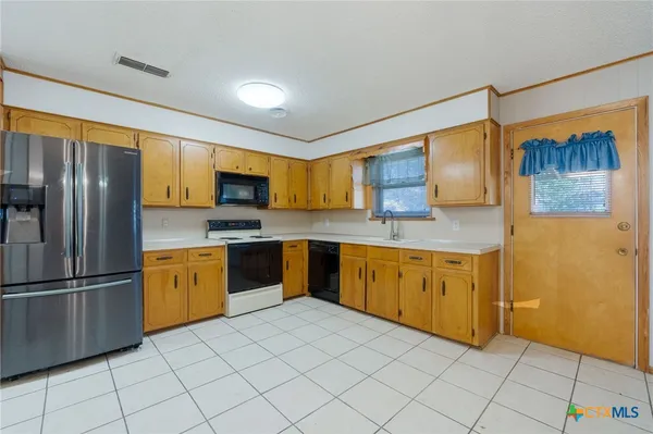a kitchen with stainless steel appliances granite countertop a refrigerator and a stove top oven