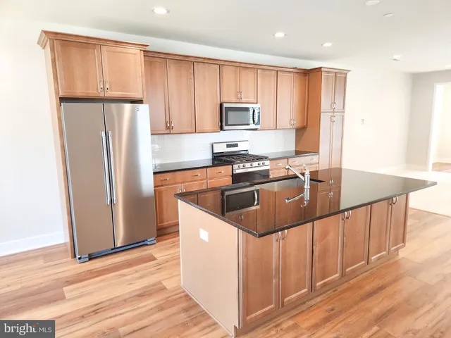 a kitchen with stainless steel appliances granite countertop a sink a stove a refrigerator and cabinets