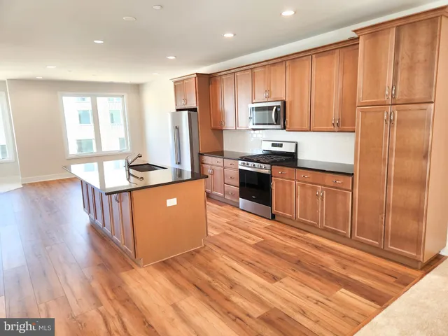 a kitchen with stainless steel appliances granite countertop a refrigerator a stove top oven a sink and dishwasher with wooden floor