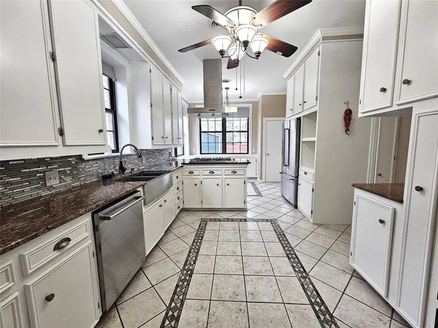 a kitchen with a sink a stove and white cabinets