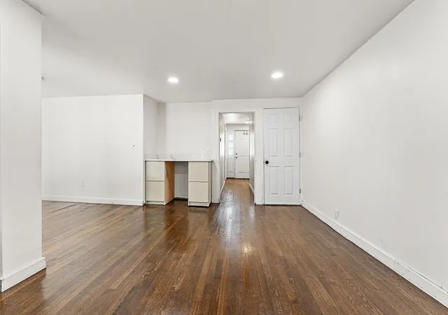a view of an empty room with wooden floor and closet