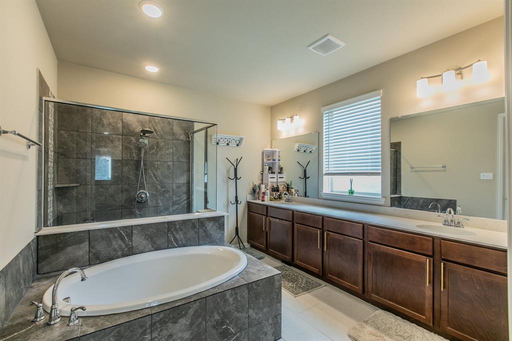 2521 Maidenhair Road Frisco, TX 75033 - Photo 10 of 39 Spacious bathroom featuring an oval soaking tub, a separate glass-enclosed shower with dark tile surround, and a double vanity with ample storage