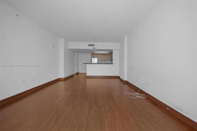 a view of empty room with wooden floor