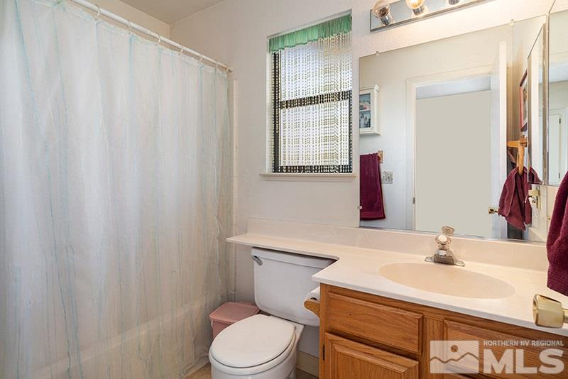 5849 Walnut Creek Road Reno, NV 89523 - Photo 10 of 20 a bathroom with a sink a toilet a mirror and shower curtain