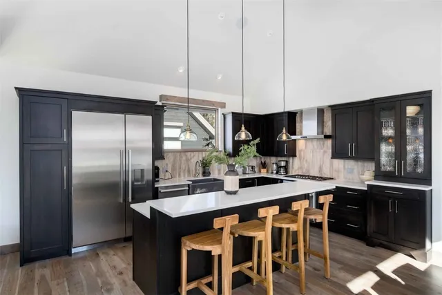 a kitchen with stainless steel appliances kitchen island granite countertop a sink a stove and refrigerator