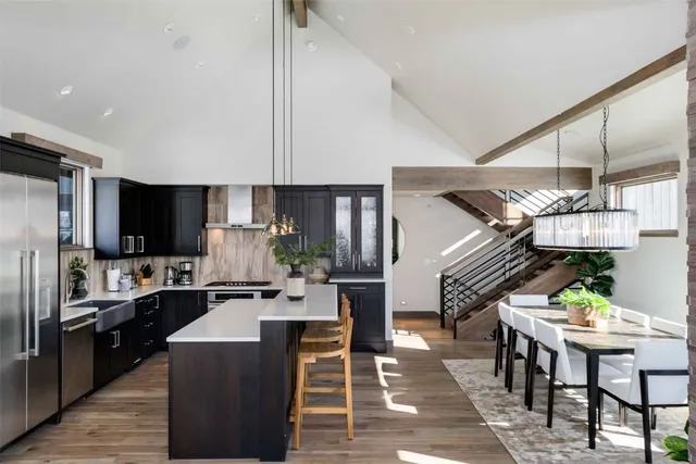 a kitchen with stainless steel appliances kitchen island granite countertop a table chairs in it and a microwave