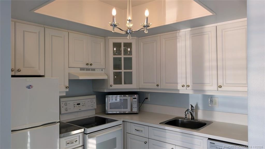 2929 Southeast Ocean Boulevard, Unit L8 Stuart, FL 34996 - Photo 21 of 32 a kitchen with stainless steel appliances granite countertop a sink a stove and white cabinets
