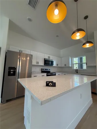 a kitchen with stainless steel appliances a stove a refrigerator a sink a dining table and chairs