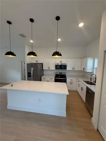 a large kitchen with a lot of stainless steel appliances and a chandelier