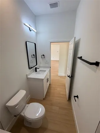 a bathroom with a toilet a sink a mirror and vanity