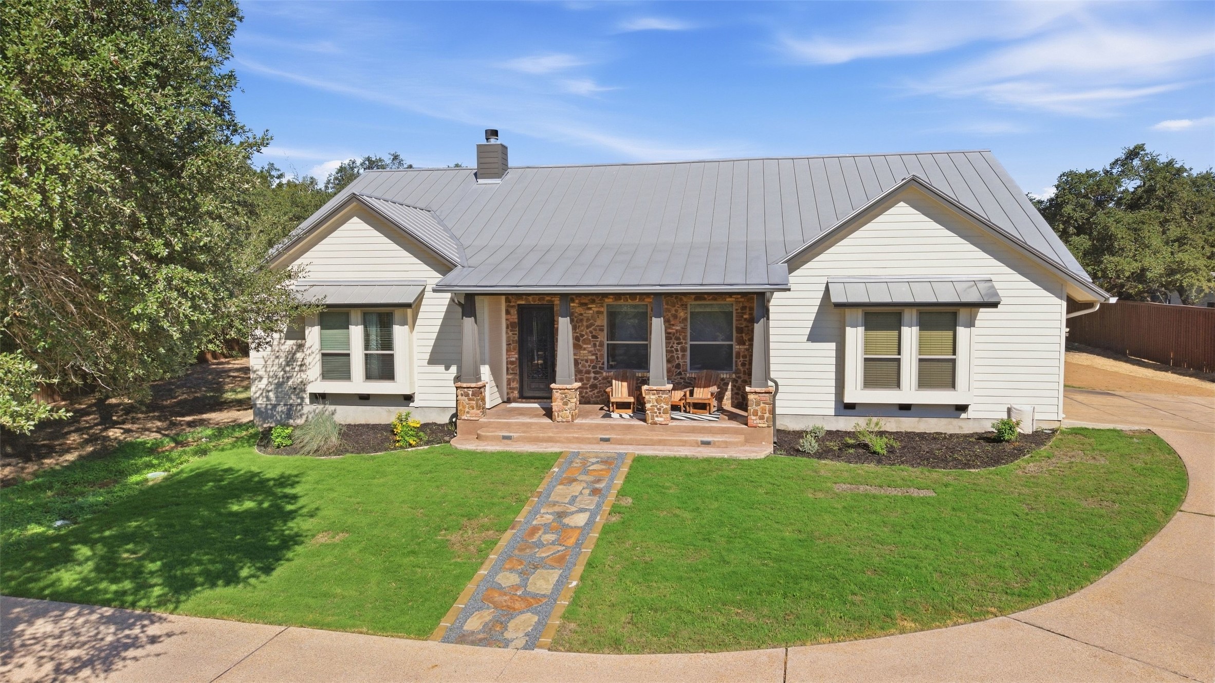 5910 Hudson Bend Road Austin, TX 78734 - Photo 1 of 40 An inviting stone-accented facade stands out against a manicured lawn and metal roofing.