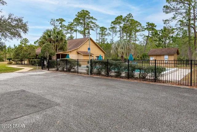 a view of a house with a small yard and large trees