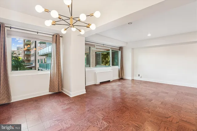 a view of an empty room with kitchen and a window