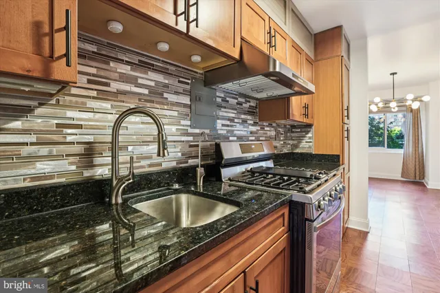 a kitchen with stainless steel appliances granite countertop a stove and a view of living room