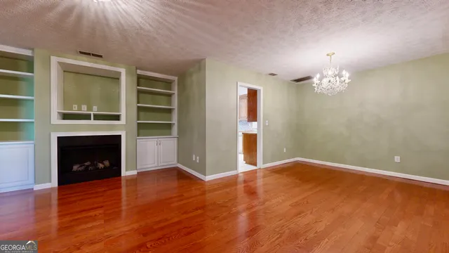 a view of an empty room with wooden floor and a fireplace