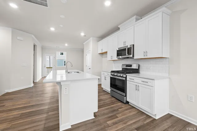 a kitchen with stainless steel appliances white cabinets a sink and a stove