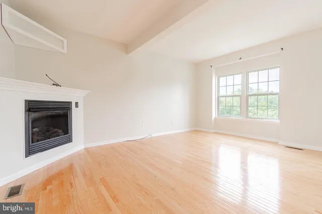 an empty room with windows and fireplace