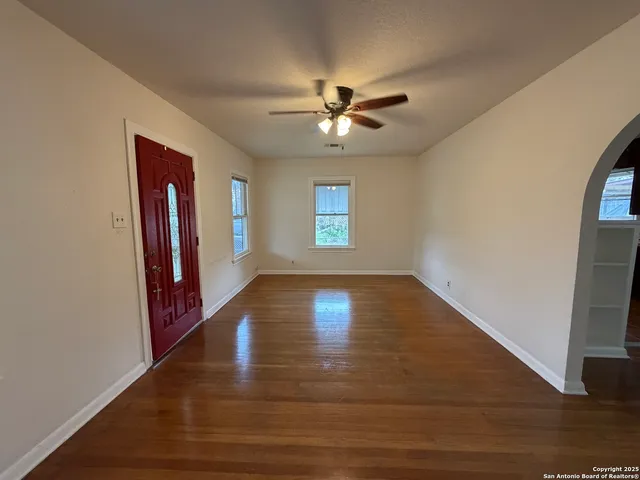 a view of empty room with wooden floor and fan
