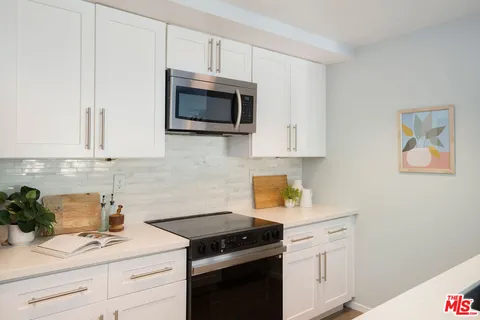 a kitchen with white cabinets and black appliances