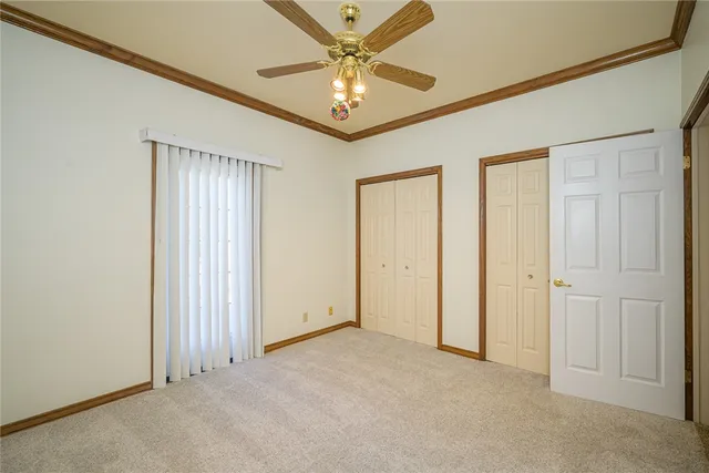 an empty room with closet and a ceiling fan