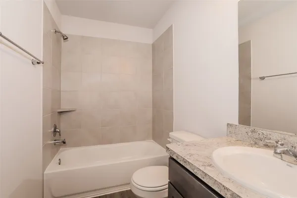 a bathroom with a granite countertop bathtub shower sink vanity mirror and toilet