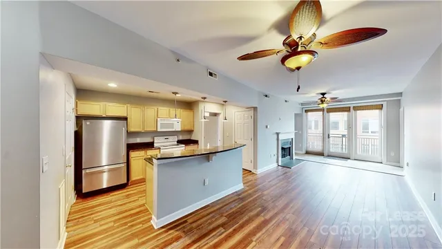 a kitchen with stainless steel appliances granite countertop a refrigerator a sink dishwasher a stove and a dining table with wooden floor