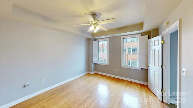 a view of empty room with wooden floor and fan